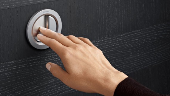 Hand pressing a Geberit remote flush button Hand pressing a Geberit remote flush button