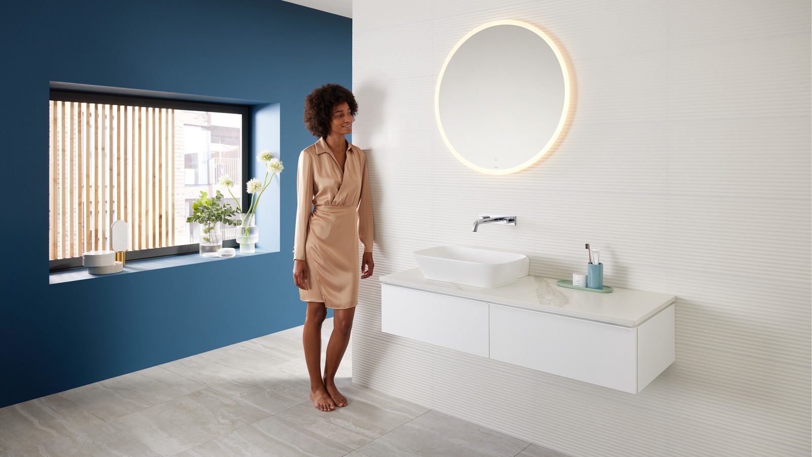 Woman leaning against the wall in the bathroom with Geberit products Woman leaning against the wall in the bathroom with Geberit products