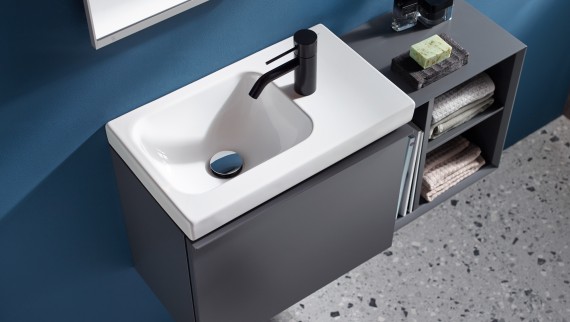 A small washbasin with side-mounted faucet in black finish A small washbasin with side-mounted faucet in black finish