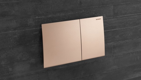 Geberit Sigma70 flush plate in red gold finish on a dark wall Geberit Sigma70 flush plate in red gold finish on a dark wall