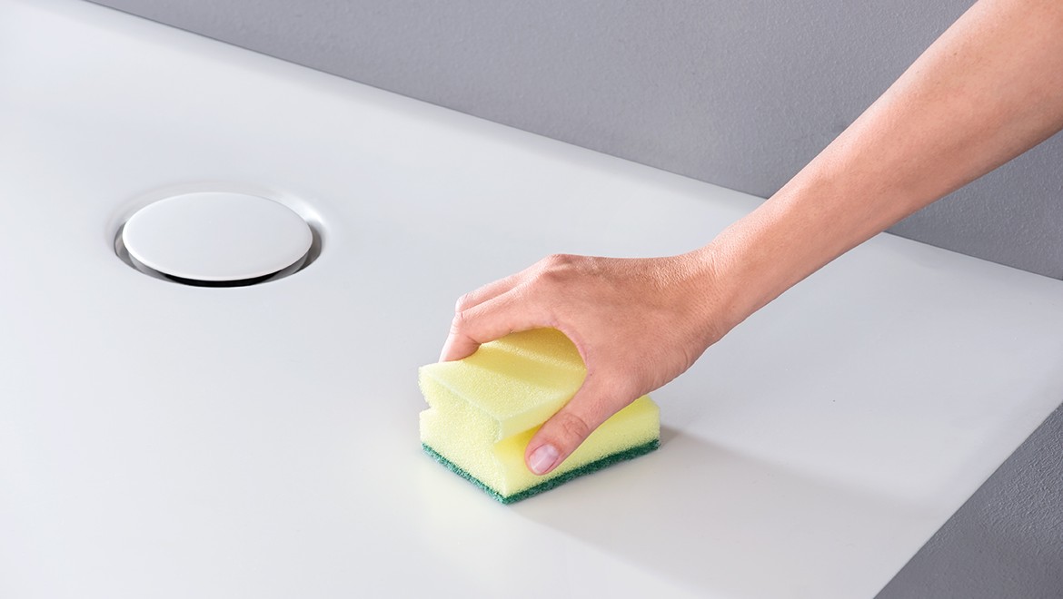 A woman using a sponge to clean the floor of a shower (© Geberit)