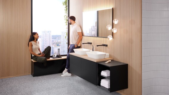 A woman and a man in a large bathroom with Geberit ONE double washbasin, Option mirror and wood elements