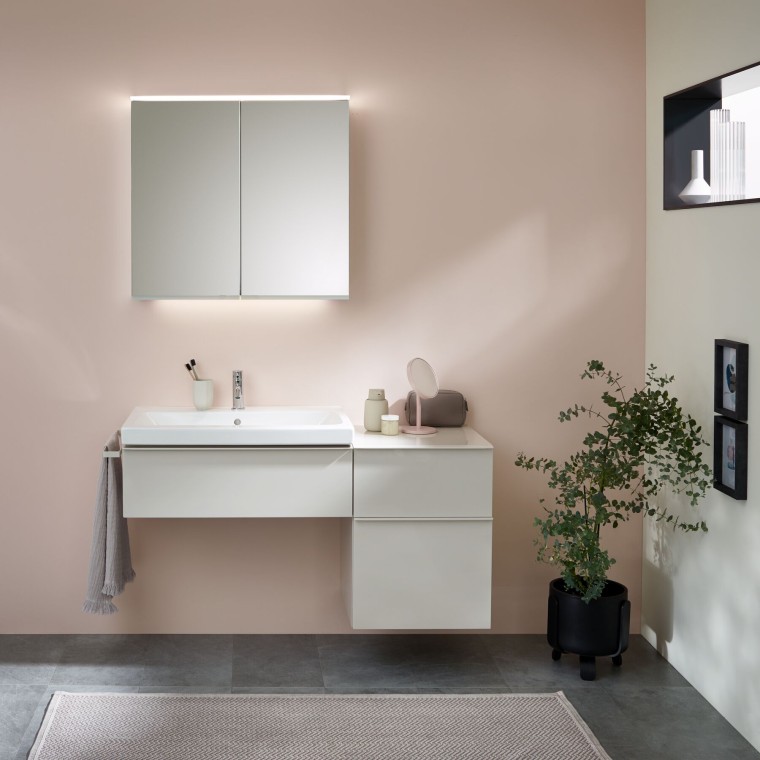 Washplace with bathroom furniture, washbasin, and mirror cabinet in front of a pastel wall