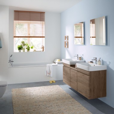 Family bathroom with light-blue wall and bathroom furniture in hickory, mirror cabinet, actuator plate, and ceramic appliances Family bathroom with light-blue wall and bathroom furniture in hickory, mirror cabinet, actuator plate, and ceramic appliances