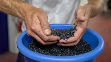 Hands holding black plastic pellets (© Ben Huggler)